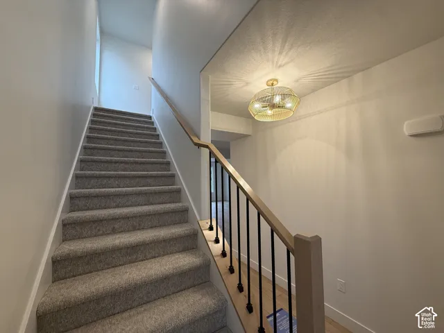 Elegant staircase featuring carpeted treads, wood-finish handrail, and black metal balustrade