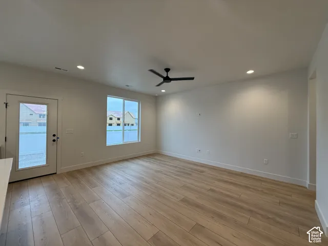 Wood-finish flooring, recessed lighting, ceiling fan, and white walls