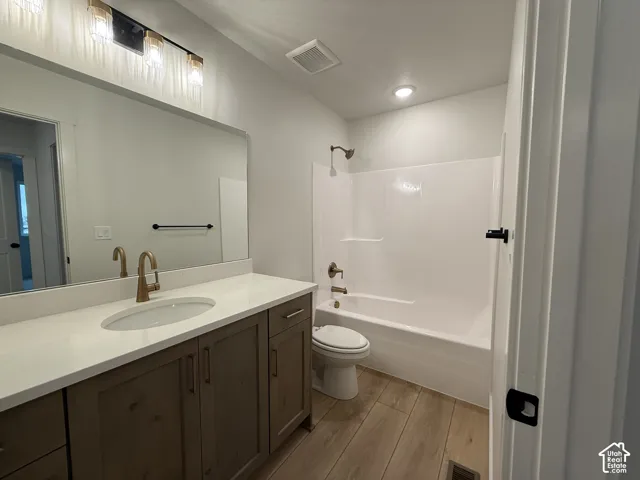 Bathroom featuring a single vanity with a white countertop, wood-finish cabinetry, a white oval sink, and a combination shower-bathtub