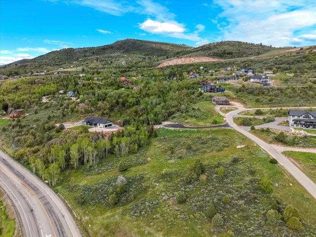 Expansive mountainous landscape featuring scattered residential properties, mature trees, and paved roadways