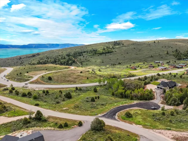 Expansive mountainous terrain featuring a prominent body of water, scattered deciduous and evergreen trees, and a network of paved roadways