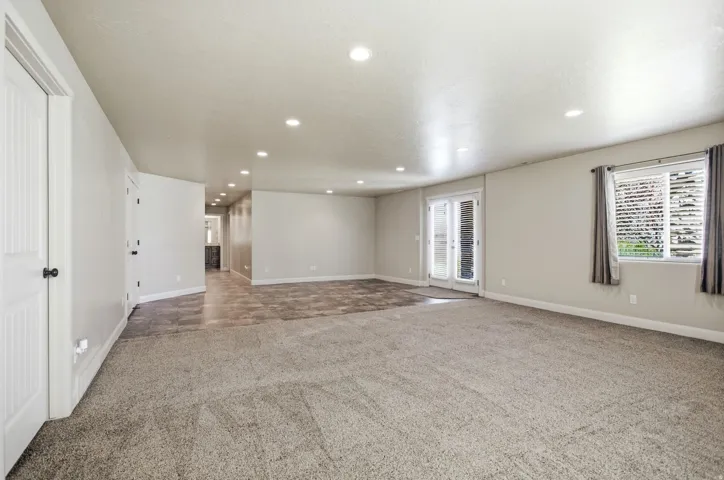 Spacious room with a mix of light-toned carpet and wood-finish flooring