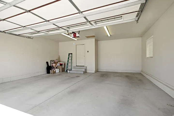 Spacious garage featuring a concrete floor, overhead fluorescent lighting, and a white interior door
