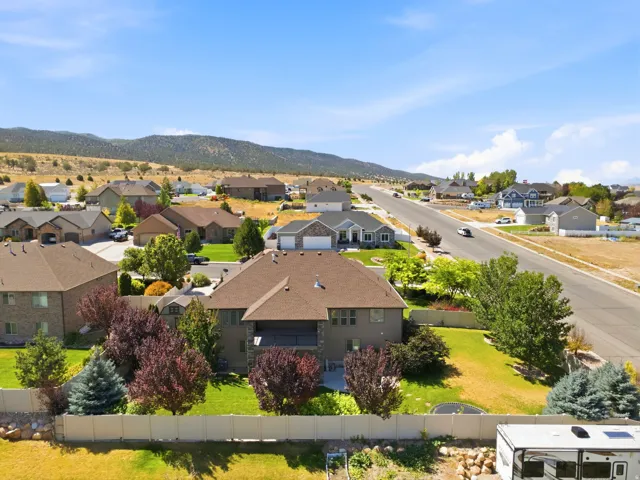 Expansive property featuring a well-maintained lawn, privacy fencing, mature landscaping, and an upper-level covered patio