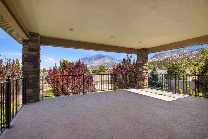 Spacious covered patio with textured concrete flooring, recessed lighting, and stone-clad columns