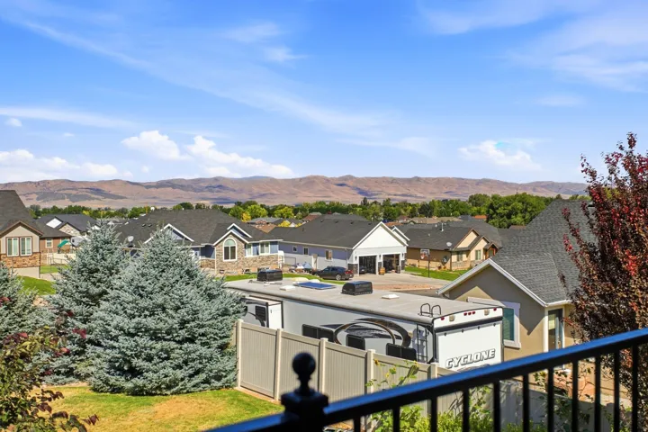 Expansive neighborhood vista featuring distant mountains, mature trees, and residential rooftops under a clear sky