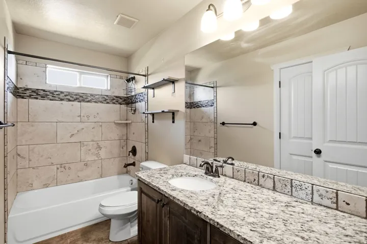 Bathroom featuring a large vanity with a granite-style countertop, a single undermount sink, and dark wood-finish cabinetry