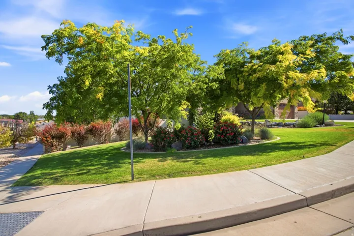 Landscaped property perimeter featuring mature trees, manicured lawn, and vibrant shrubs