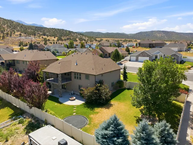 Expansive backyard featuring a stone patio with a built-in fire pit, a covered outdoor deck, and a lower-level covered patio