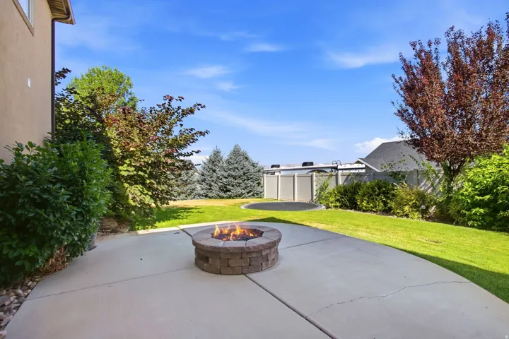 Expansive concrete patio featuring a built-in stone fire pit
