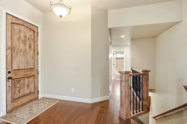 Entryway featuring a wood-finish door with black hardware, complementing wood-finish flooring, and a decorative overhead light fixture