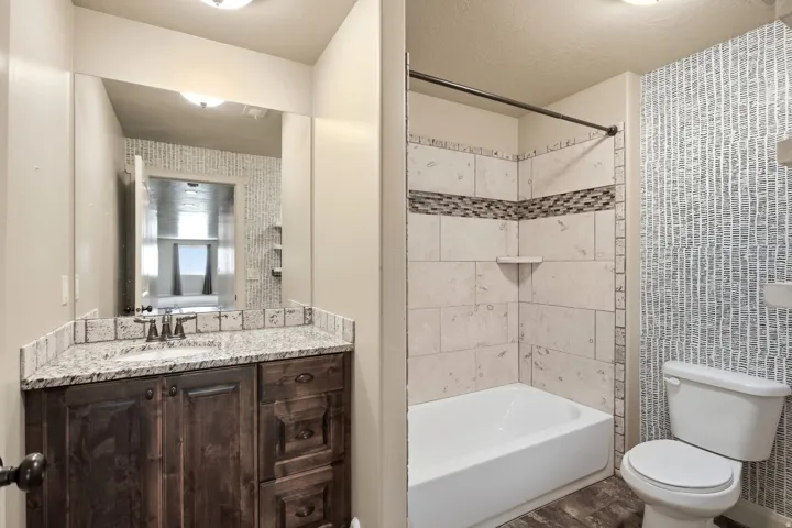 Bathroom featuring a dark wood-finish vanity with a granite countertop and an undermount sink