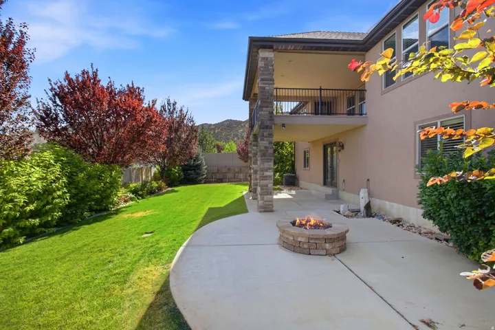 Spacious concrete patio featuring a built-in stone fire pit