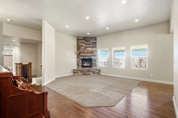 Spacious living area featuring a corner stone-faced fireplace with a wood mantel