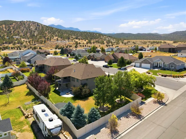 Aerial view showcasing a residential neighborhood with established homes, mature landscaping, and mountain backdrops
