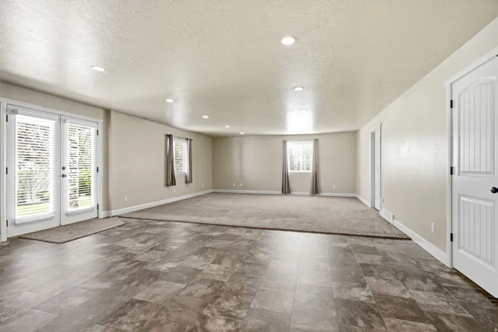 Spacious interior featuring a blend of tile-look flooring and carpet, multiple windows with blinds, recessed lighting, and a paneled interior door