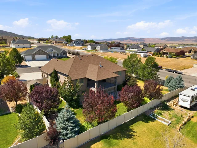 Expansive property featuring a multi-level home with a brown shingle roof, a two-story rear deck, a fenced backyard, and established landscaping with varied tree species
