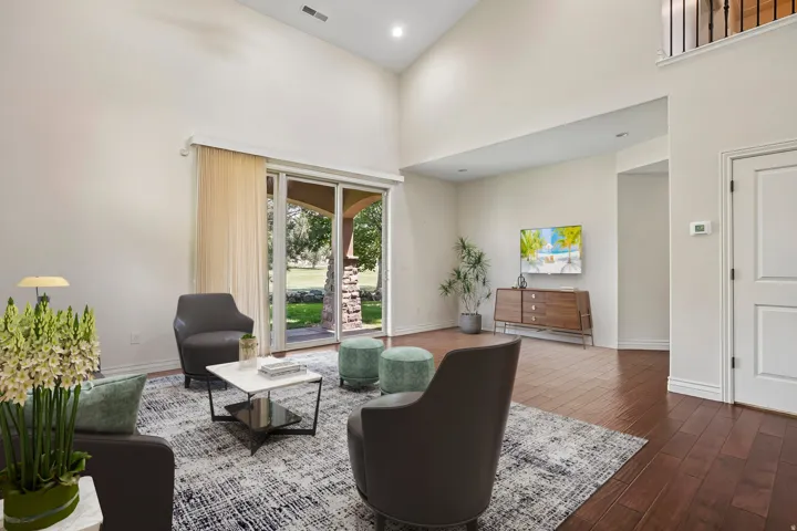 Expansive living area featuring soaring vaulted ceilings, rich wood-finish flooring, and a large sliding glass door opening to outdoor space