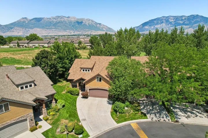 Contemporary residence featuring a two-car garage, dormer windows, and a curved driveway