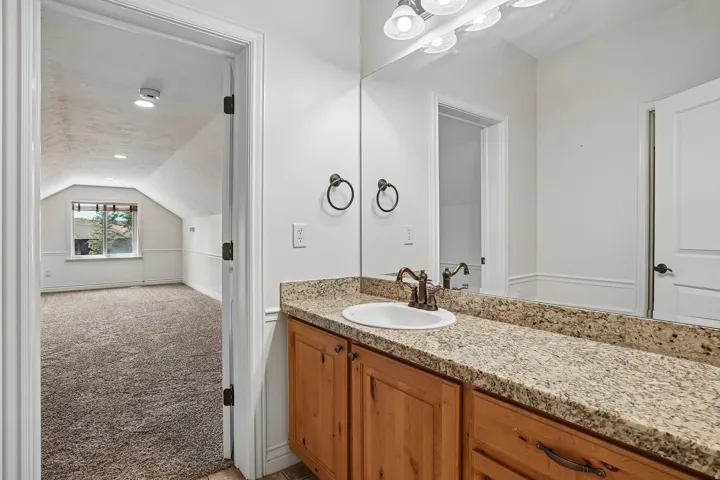 Bathroom vanity featuring a speckled countertop, undermount sink, and bronze-finish hardware