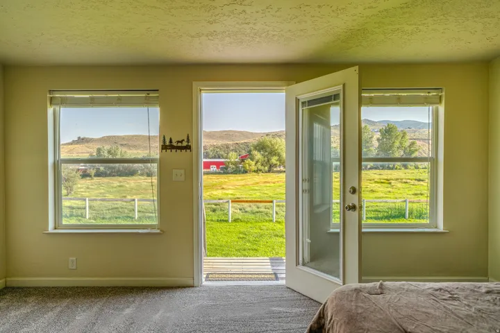 Owners Suite featuring a glass-paneled door opening to a deck, two windows, and textured carpeting
