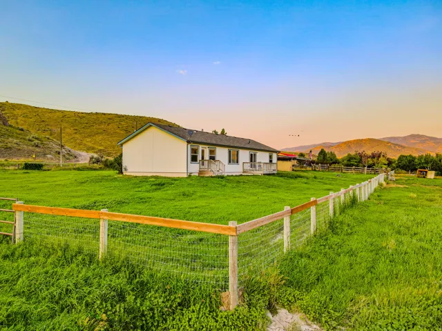 Spacious property featuring a white exterior home with multiple windows, a rear deck, and a fenced perimeter