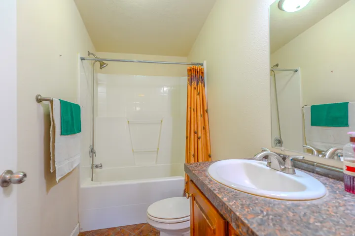 Bathroom featuring a white tub/shower combination with a chrome showerhead, a toilet, and a vanity with a white basin sink and chrome faucet