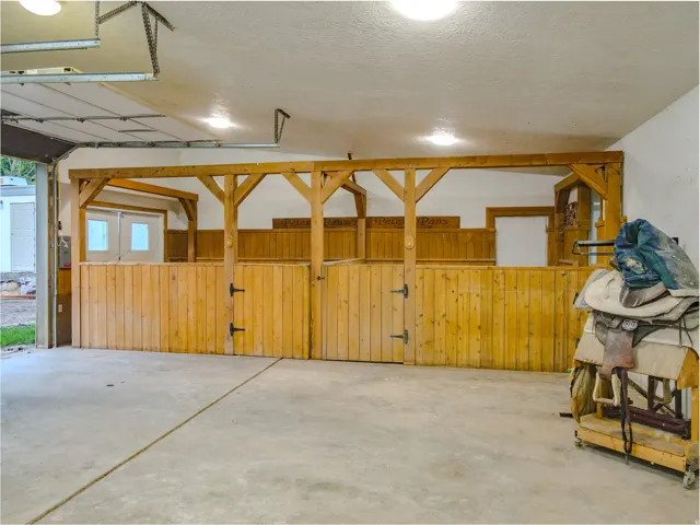 Garage space featuring concrete flooring, overhead garage door, built-in wooden stalls, and recessed ceiling lighting