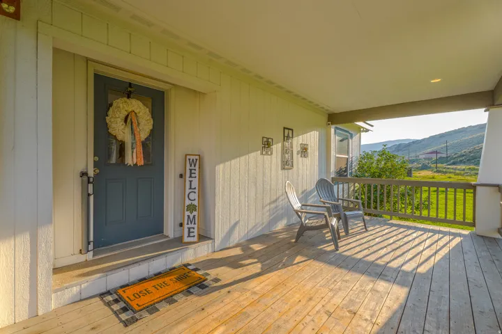 Covered front porch featuring wood-finish decking and a railing system