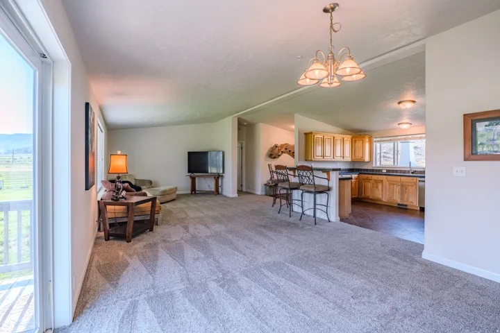 Open-concept living area featuring a kitchen with wood cabinetry, a breakfast bar, and a dining area with a chandelier