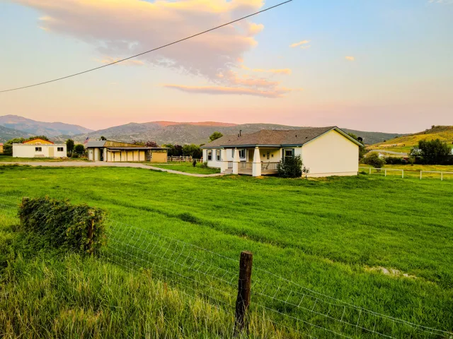 Expansive grassy grounds featuring a single-story residence with a covered porch