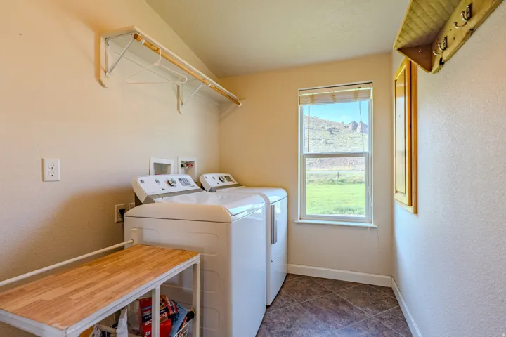 Laundry area featuring a window, tile flooring, and a wall-mounted shelving unit