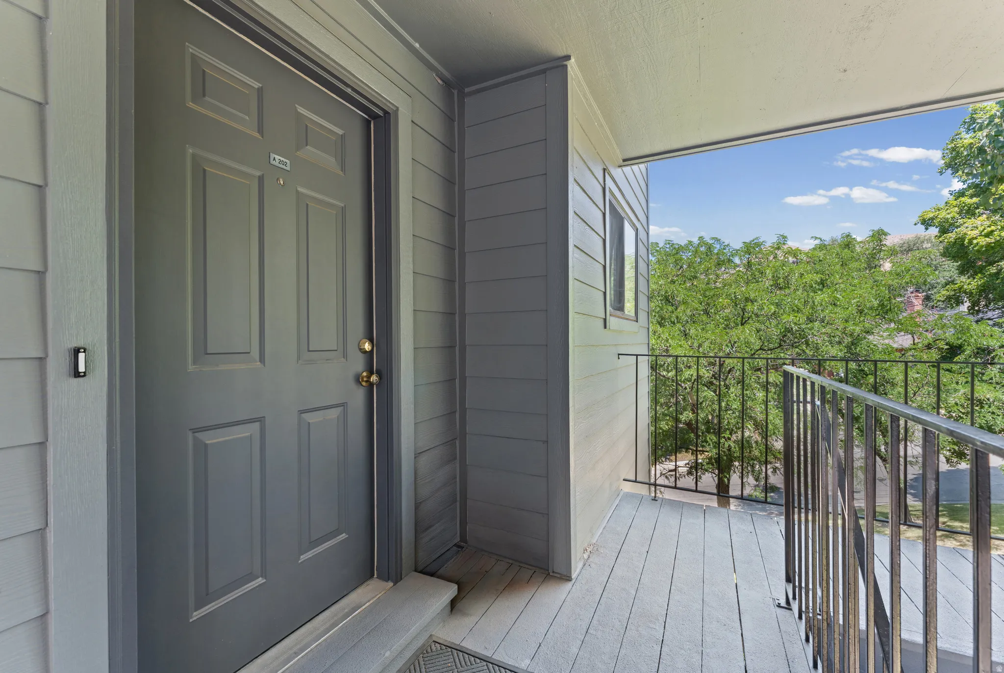 Private balcony with painted wood-finish flooring and a black metal railing