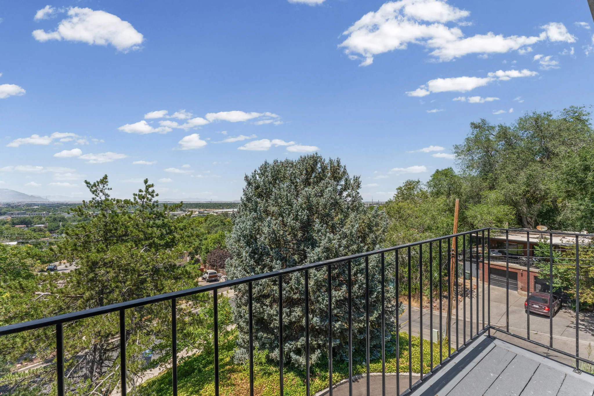 Balcony with black metal railing overlooking a verdant landscape with distant mountains