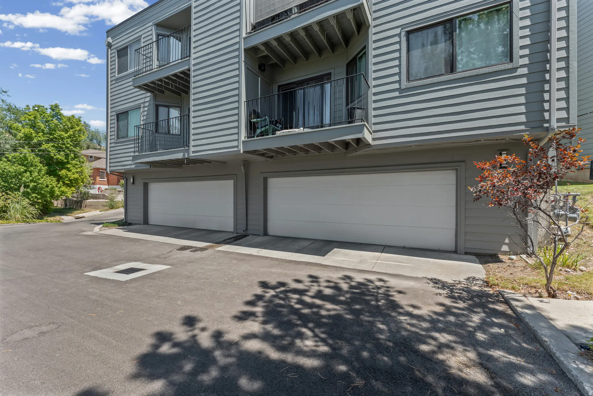 Multi-level building with gray horizontal siding and individual garage doors
