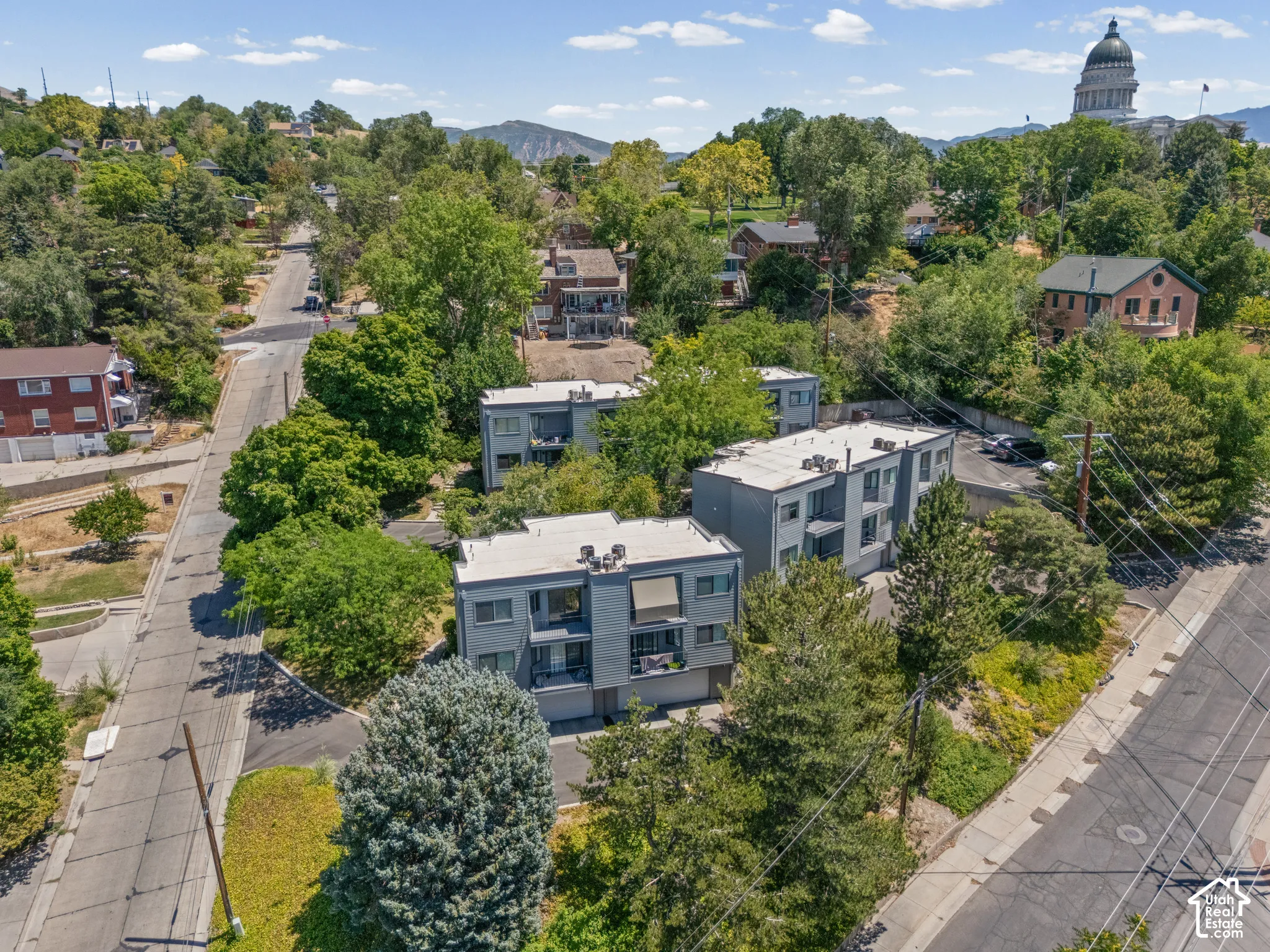 Contemporary multi-story building featuring gray exterior siding, flat roofline, and integrated balconies