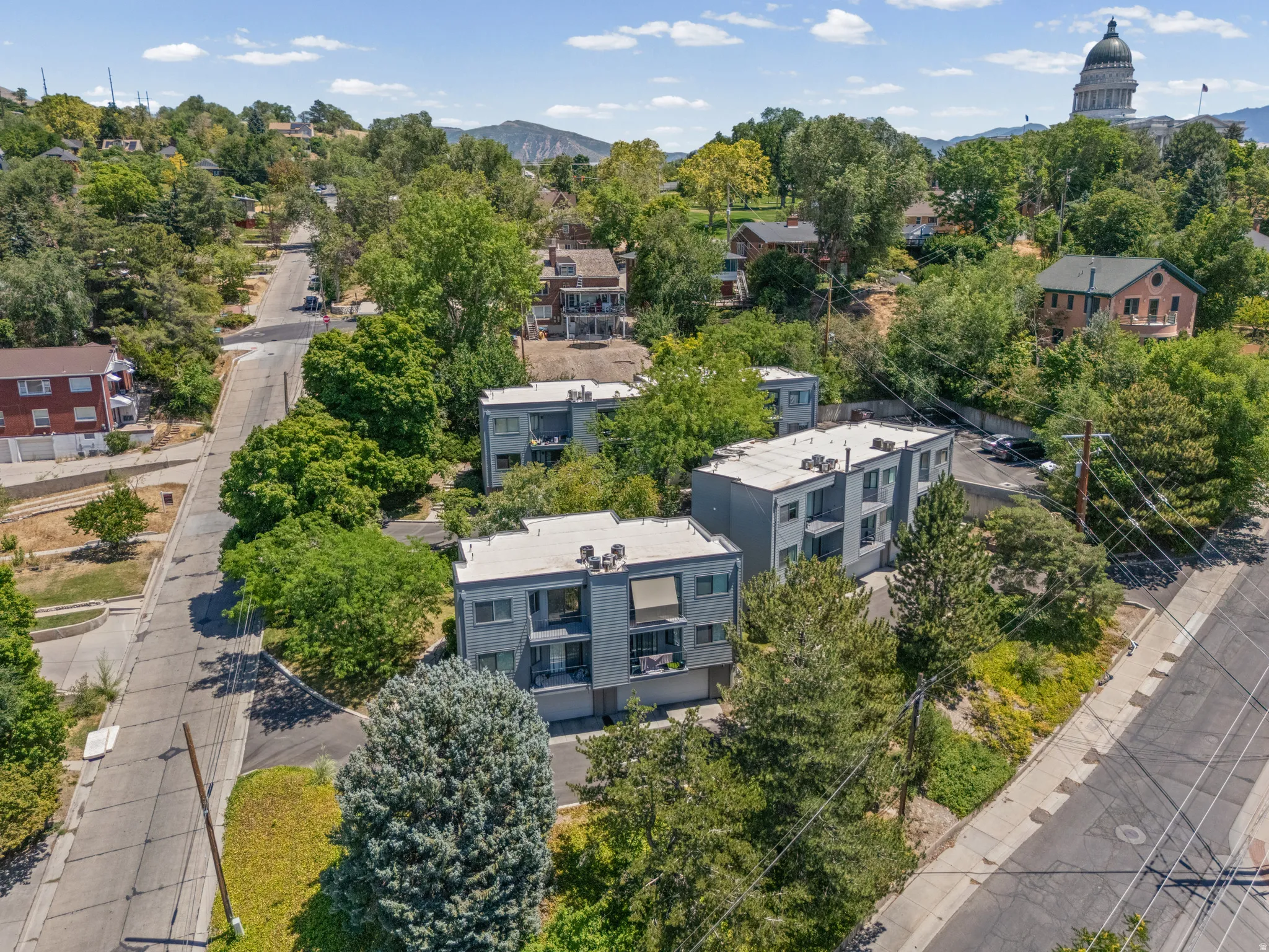 Contemporary multi-story building featuring gray exterior siding, flat roofline, and integrated balconies