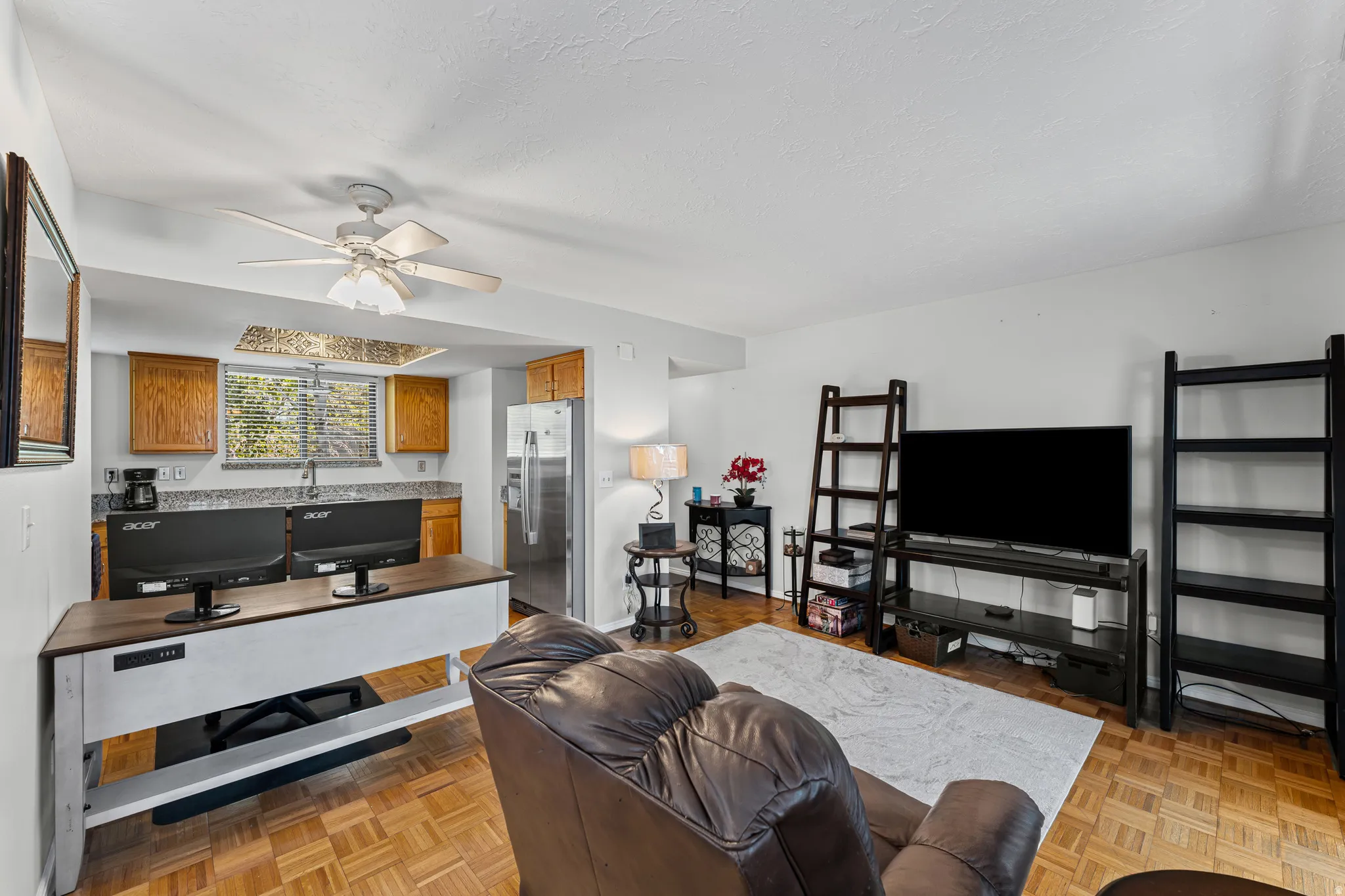 Open-concept living space with wood-finish flooring, a ceiling fan, and white walls