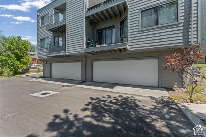 Multi-level building with gray horizontal siding and individual garage doors