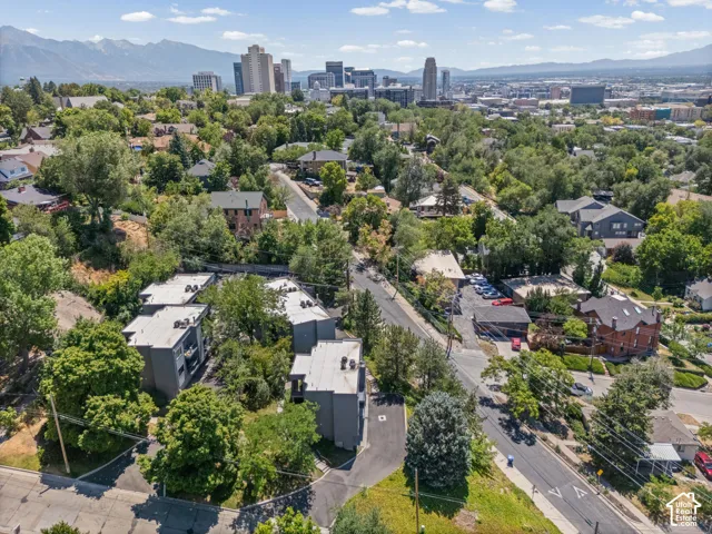 Low-rise multi-unit buildings with flat roofs and dark-toned facades, surrounded by mature trees