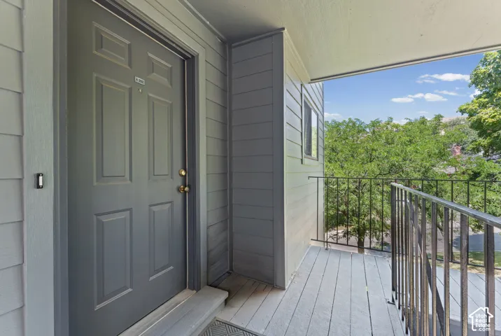 Private balcony with painted wood-finish flooring and a black metal railing