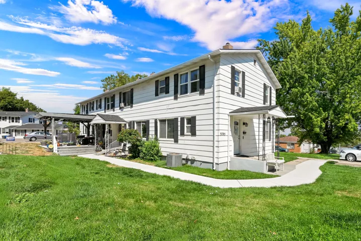 Classic Colonial-style home featuring white horizontal siding, black shutters, and a gabled roofline