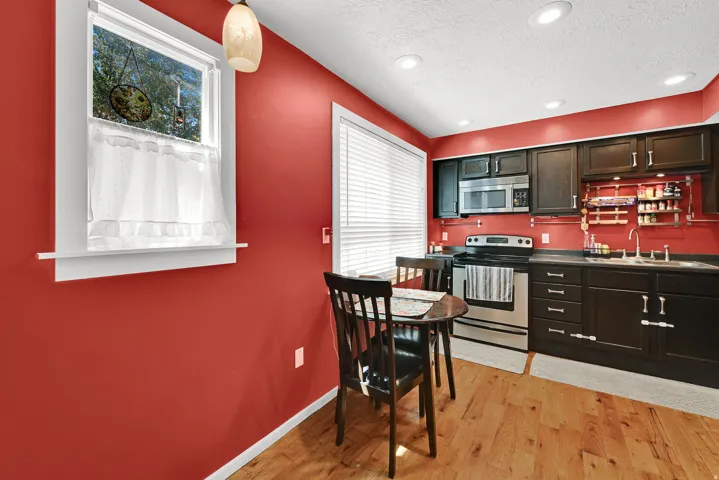 Kitchen featuring dark wood cabinetry, stainless steel appliances, solid surface countertops, and light wood-finish flooring