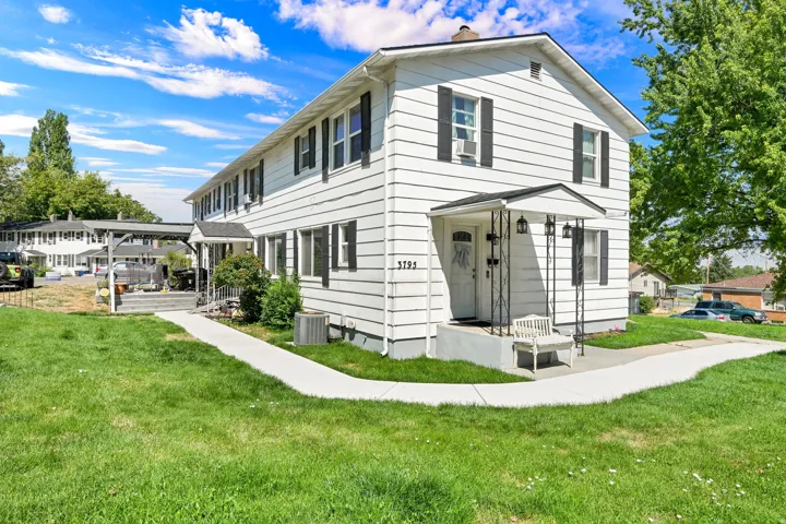 White siding exterior with black window shutters and a covered entry