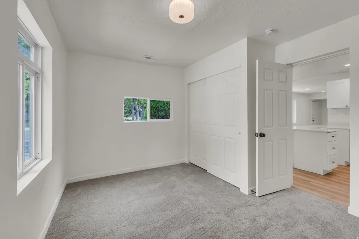 Spacious room featuring neutral carpeting, a dual-pane window, and a large sliding closet door