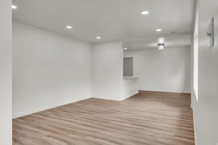 Open-concept living area featuring wood-finish flooring, recessed lighting, and a white color palette