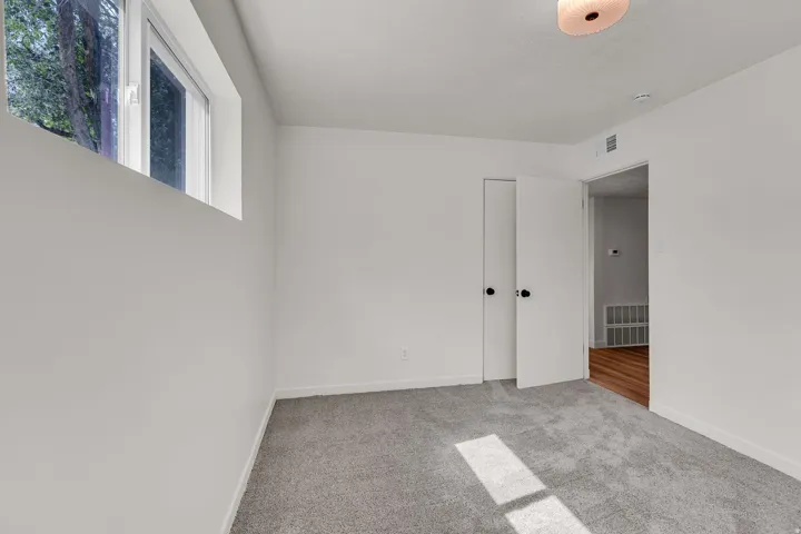 Spacious interior room featuring light gray carpet flooring and white painted walls