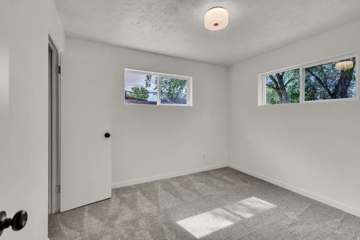 Room with neutral-toned walls, gray patterned carpeting, and white baseboards