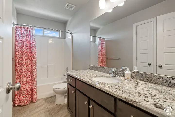 Spa-inspired bathroom featuring a dual-sink vanity with speckled stone countertops, dark cabinetry, and brushed nickel hardware