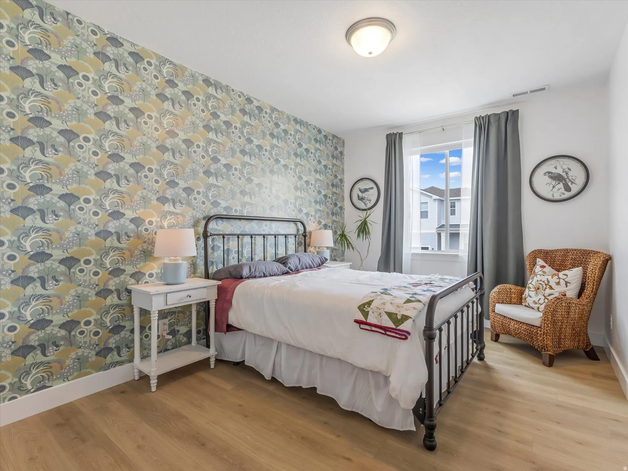 Accent wall with patterned wallpaper, wood-finish flooring, white trim, ceiling-mounted light fixture, and a window with white casing